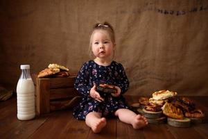 petite fille dans la cuisine mange des pâtisseries sucrées. photo