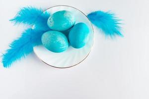 composition d'oeufs de pâques bleus et de plumes sur fond clair. photo