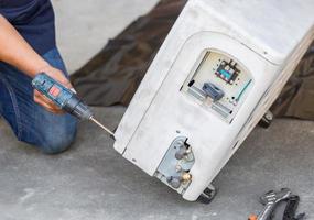 réparation de la climatisation à mise au point sélective, les mains d'un technicien à l'aide d'un tournevis fixant un système de climatisation moderne photo