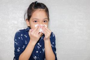 portrait d'une petite fille essuyer le mucus et regardant la caméra avec un arrière-plan flou photo