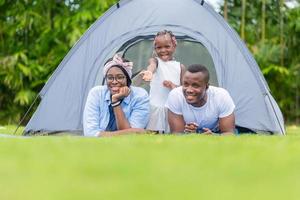 joyeuse famille afro-américaine profitant du parc, mère père et fille jouant au camping en plein air, concepts de famille de bonheur photo