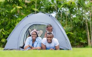 joyeuse famille afro-américaine profitant du parc, mère père et fille jouant au camping en plein air, concepts de famille de bonheur photo