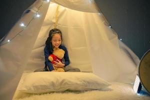 petite fille lisant un livre dans une tente, enfant heureux jouant à la maison, drôle d'enfant charmant s'amusant dans la chambre des enfants. photo