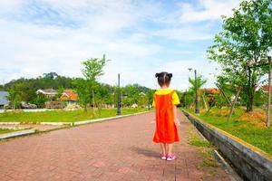 jolie petite fille porte une tenue gokowa jaune-orange, mugunghwa dans un parc public. robe de mode pour filles et adolescentes. photo