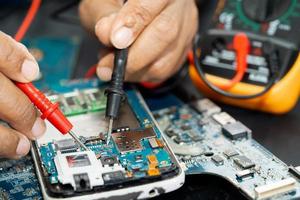 technicien réparant l'intérieur du téléphone portable en fer à souder. circuit intégré. le concept de données, de matériel, de technologie. photo