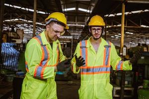 ingénierie de l'industrie et travail d'équipe portant un contrôle uniforme de sécurité faisant fonctionner la machine de meulage de tour travaillant dans l'usine de l'industrie. photo