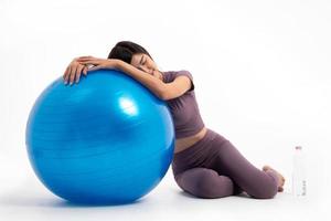 une femme asiatique en bonne santé se repose en se couchant sur le ballon après une séance d'entraînement avec fitball sur fond blanc isolé, le concept de bonne santé commence par l'exercice. photo