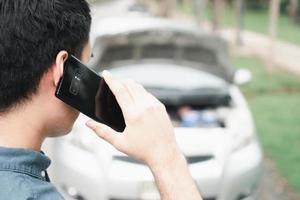 homme asiatique utilisant un téléphone portable appelant à l'aide après une panne de voiture dans la rue. concept de problème de moteur de véhicule ou d'accident et aide d'urgence d'un mécanicien professionnel photo