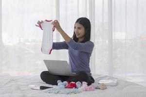 les mères asiatiques choisissent des vêtements de bébé inutilisés pour les vendre en ligne en tant qu'articles d'occasion en bon état. photo