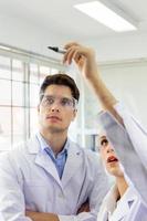 gros plan, un groupe de scientifiques, de jeunes femmes et de jeunes hommes enregistrent des formules sur un tableau en verre. photo