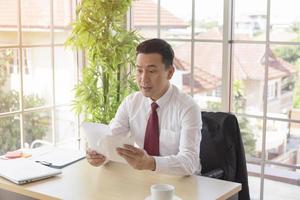 un homme dans une entreprise asiatique reçoit des documents importants sur son bureau avec une expression choquée. photo