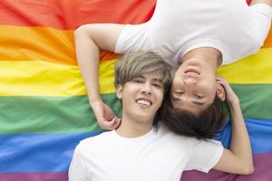 des couples masculins avec des hommes asiatiques dorment sur un drapeau multicolore avec un logo lgbt montrant des hommes ouvertement homosexuels acceptant les concepts lgbt. photo
