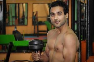 homme indien dans la salle de gym avec haltère de gym photo