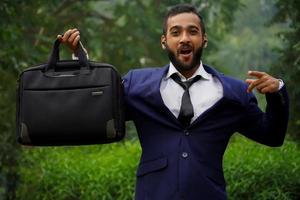 gros plan d'un homme d'affaires indien prospère en costume debout sur le jardin du bureau avec une mallette en cuir noir dans les mains. jeune travailleur occupé marchant à l'extérieur. photo