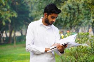 étudiant indien lisant un livre près du campus universitaire photo