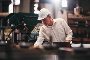 ouvrier d'usine vérifiant le processus de la machine électrique sur le chantier industriel, portant un casque de protection pour la sécurité photo