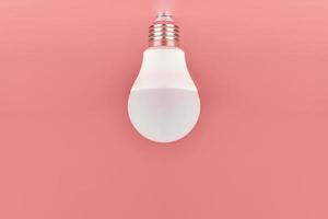 ampoule à économie d'énergie, espace de copie, fond rose. concept d'idée minimale. photo