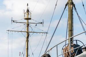 mât de navire de frégate, chaloupe ou cuirassé de la marine. poteau de mât en métal. navire attend le capitaine à quai. voiles baissées, ciel bleu sur fond. photo