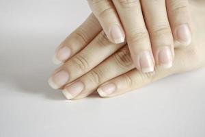 gros plan de belles mains et ongles de femme sur fond blanc, concept de soins de santé de l'ongle. photo