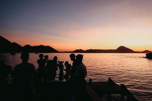 silhouette noire de touristes se rassemblant et faisant une séance photo avec la mer et les collines à labuan bajo