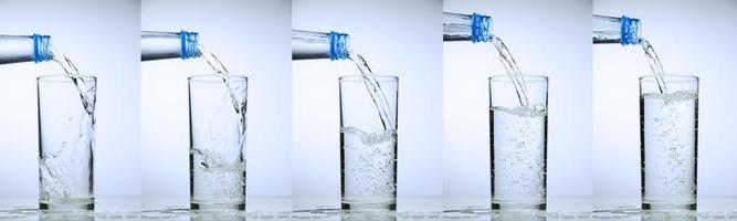 le verre se remplit d'eau. collection d'éclaboussures d'eau sur fond blanc. photo