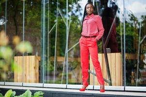 jolies tresses affaires femme afro-américaine brillante personne autoritaire amicale porter bureau chemise rouge et pantalon. photo