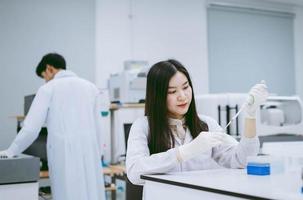 jeune scientifique médicale travaillant dans un laboratoire médical, jeune femme scientifique utilisant une pipette automatique pour transférer un échantillon photo