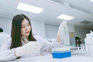 jeune scientifique médicale travaillant dans un laboratoire médical, jeune femme scientifique utilisant une pipette automatique pour transférer un échantillon photo