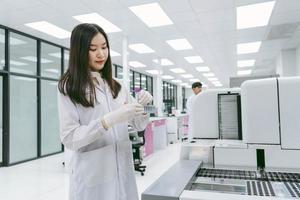 jeune femme scientifique travaillant avec un rapport d'analyseur de sang automatisé dans un laboratoire médical