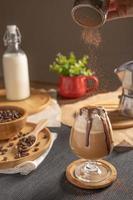café moka glacé servi avec garniture de crème fouettée et sirop de chocolat dans un verre à vin placé sur une table en bois