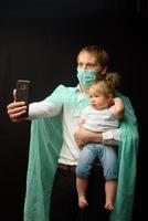 père dans un masque médical tient sa petite fille. le concept de protection des enfants pendant l'épidémie de coronavirus photo