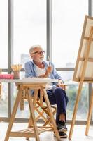 homme âgé peignant sur une toile, homme mûr souriant peignant sur toile à la maison, concepts de retraite heureuse photo