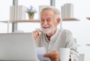 portrait d'un homme âgé utilisant un ordinateur portable à la maison, homme âgé dans le salon avec un ordinateur portable naviguant sur Internet sur un gadget informatique moderne photo