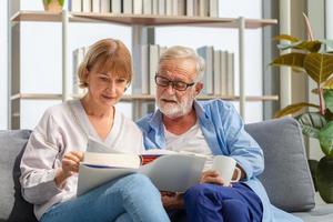 portrait d'un couple de personnes âgées heureux dans le salon, d'une femme âgée et d'un homme lisant un livre sur un canapé confortable à la maison, concepts de famille heureuse photo