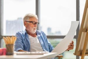 homme âgé peignant sur une toile, peintre senior regardant une peinture, concepts de retraite heureuse photo