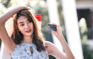 spectacle de carte de crédit par une jeune femme asiatique souriante. photo