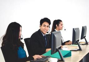 sourire positif jeune homme d'affaires asiatique utilisant un casque et un ordinateur pour le soutien.