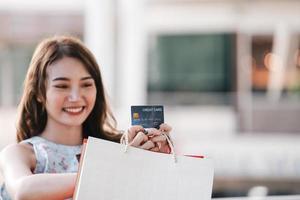 spectacle de carte de crédit par une jeune femme asiatique souriante. photo