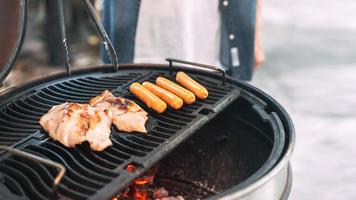 main d'homme grillant un barbecue en feu dans l'arrière-cour le jour photo