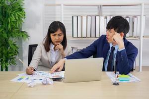 deux asiatiques du personnel masculin et féminin ont aidé à planifier une table pleine de documents et de tablettes, de cahiers. photo