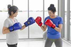 deux femmes asiatiques d'âge moyen faisant des exercices de boxe dans la salle de gym. photo