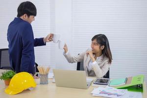 une jeune femme d'affaires asiatique jeune et professionnelle est assise à son bureau et cogne une tasse de café avec un employé de bureau masculin travaillant ensemble. photo