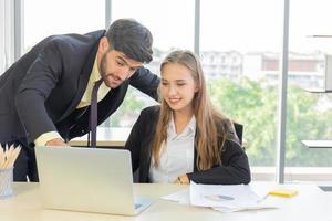 deux jeunes hommes d'affaires, hommes et femmes, travaillent au bureau avec une tablette et des documents d'accompagnement sur le bureau avec sourires et bonheur. photo