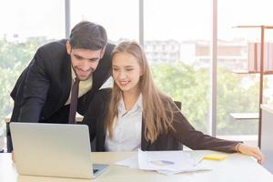 deux jeunes hommes d'affaires, hommes et femmes, travaillent au bureau avec une tablette et des documents d'accompagnement sur le bureau avec sourires et bonheur. photo