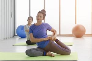 deux femmes asiatiques d'âge moyen faisant du yoga assises sur un tapis en caoutchouc dans une salle de sport. photo