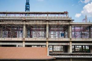 structure d'un grand bâtiment avec un ouvrier travaillant, une grue et un échafaudage sur un chantier de construction photo