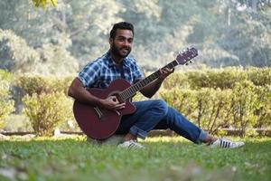 jeune garçon avec sa guitare et jouant de la guitare dans le parc photo