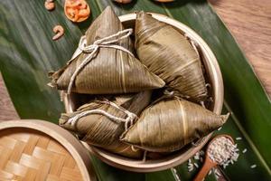 zongzi, boulettes de riz cuites à la vapeur sur des feuilles de bambou de table en bois, nourriture dans le concept duanwu du festival des bateaux-dragons, gros plan, espace pour copie, vue de dessus, pose à plat photo