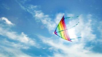 cerf-volant arc-en-ciel volant dans le ciel bleu avec des nuages photo