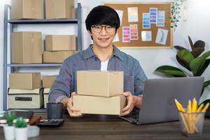 homme d'affaires asiatique startup PME entrepreneur ou indépendant travaillant dans une boîte en carton prépare la boîte de livraison pour le client, la vente en ligne, le commerce électronique, l'emballage et le concept d'expédition. photo